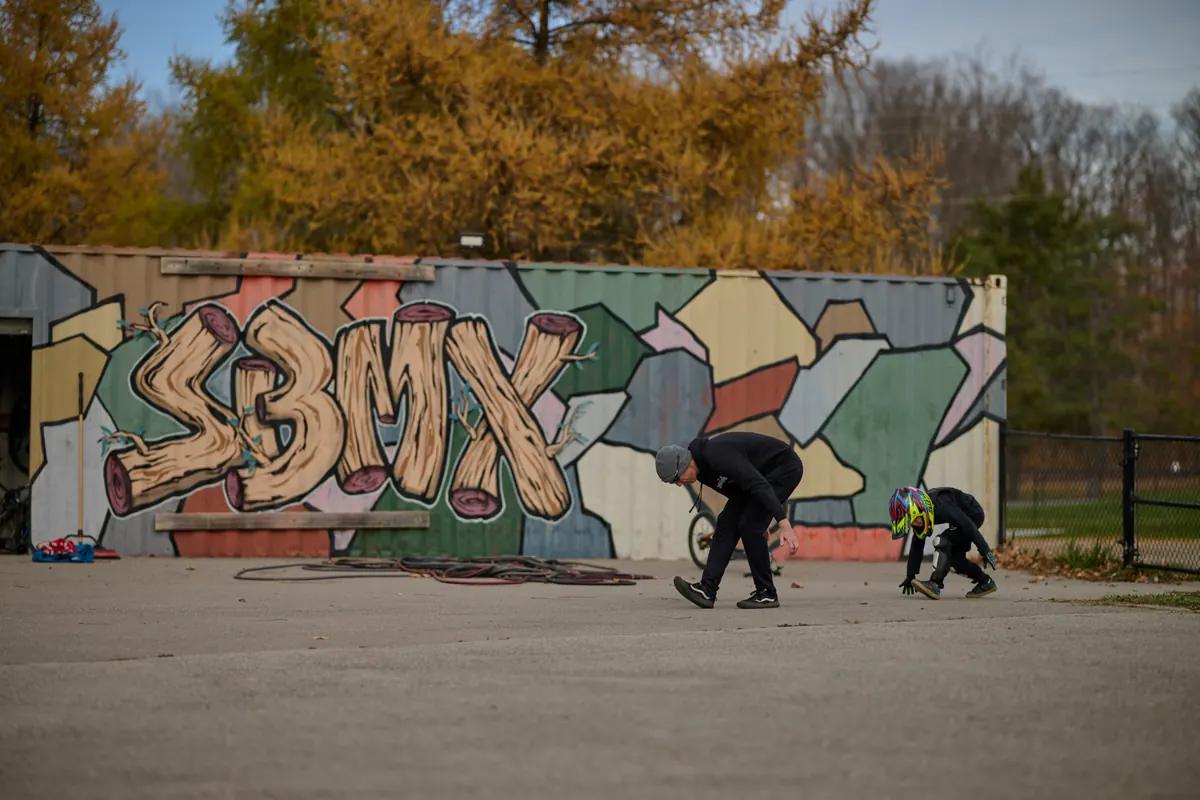 一位 XKIDS 小骑手在 BMX 场地的涂鸦墙旁经过,社区训练时刻。