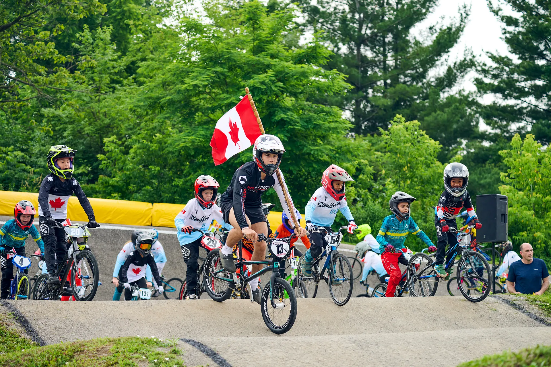 一排 XKIDS 小学员在 BMX 比赛起点列队,身后飘扬着加拿大国旗。