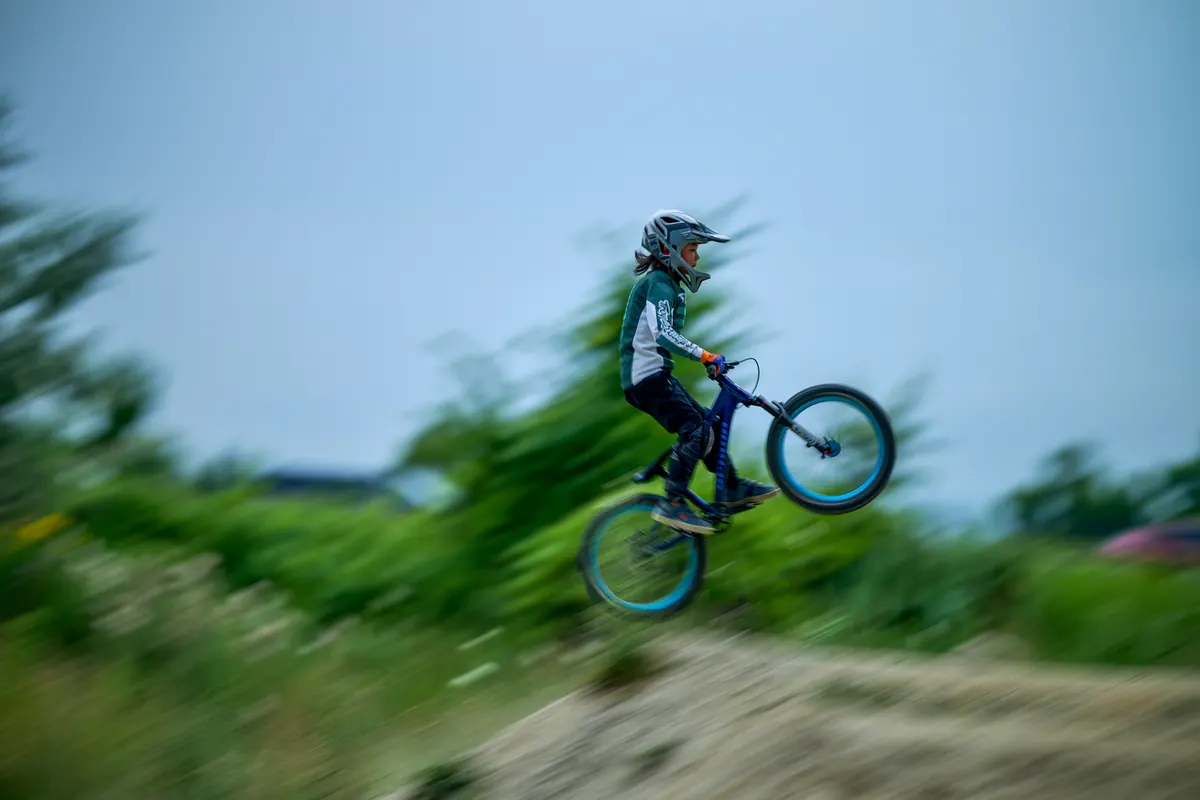 A young XKIDS mountain bike rider catching air over a feature.